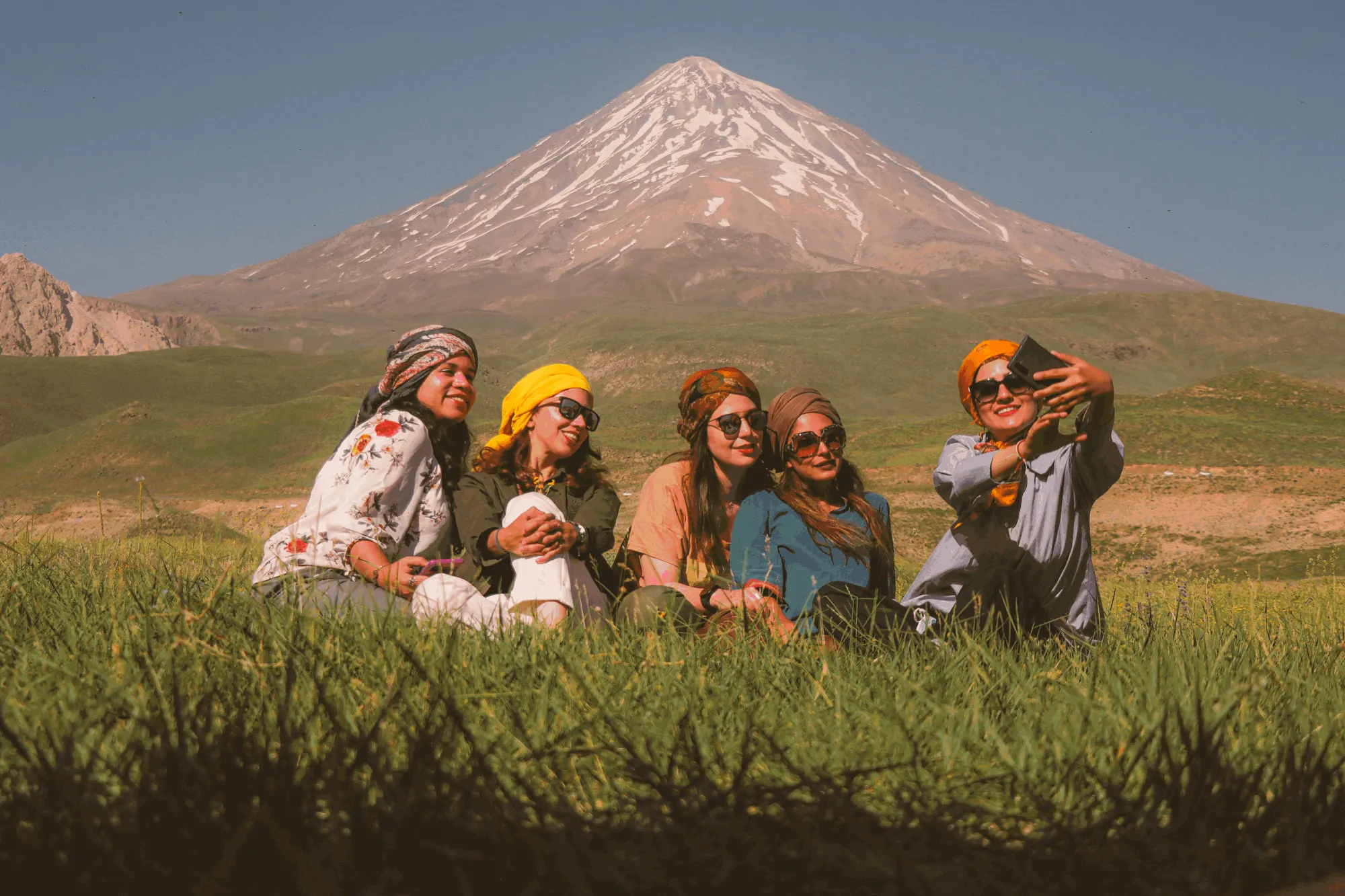 Group of Indian women friends taking a selfie together in front of a snow-capped mountain